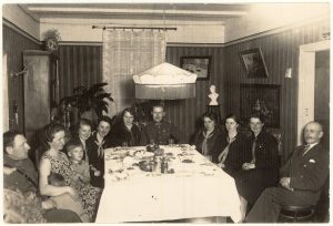 Svečiuose pas I pėstininkų divizijos štabo adjutanto kapitono Juozo Rinkevičiaus šeimą. Sėdi gale stalo centre karininkas Juozas Rinkevičius su žmona, 1-as iš kairės – leitenantas Vladas Aižinas su žmona Ona Kazokaite-Aižiniene ir vaikais. Panevėžys, 1932 05 08. PAVB F8-88