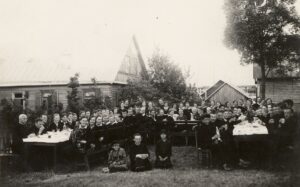 Panevėžio ateitininkų abiturientų išleistuvės. Kairėje stalo pusėje sėdi iš kairės: kunigas Jurgis Žitkevičius, kunigas Juozapas Ruškys, kunigas Leonas Lukošiūnas (vėliau - Lumas). Centre, ant žemės sėdi kunigas Alfonsas Lipniūnas. Stalo gale, centre: vyskupas Kazimieras Paltarokas ir Ateitininkų federacijos Garbės pirmininkas prof. Pranas Dovydaitis. Panevėžys. 1932 m. Panevėžio apskrities Gabrielės Petkevičaitės-Bitės viešosios bibliotekos skaitmeninis archyvas